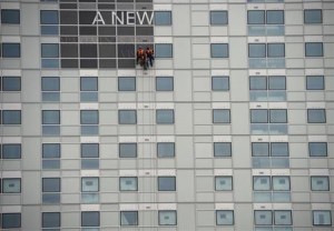 Workers put up a sign on a newly constructed office and apartment building in the heart of London